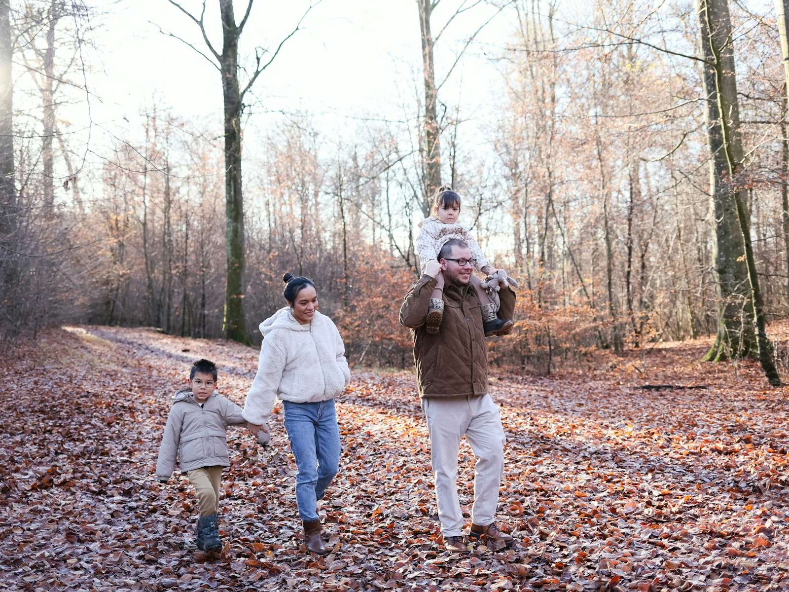 Famille marchant dans une forêt d'automne, enfant sur les épaules