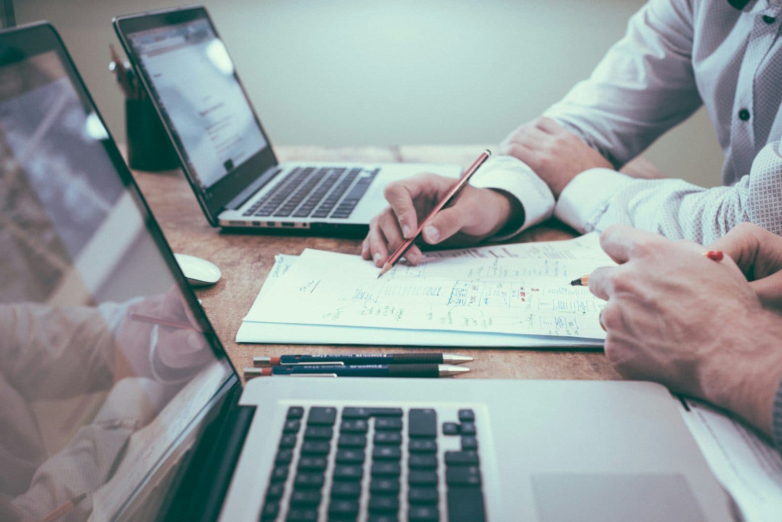 Associés révisant un plan sur un bureau avec ordinateurs